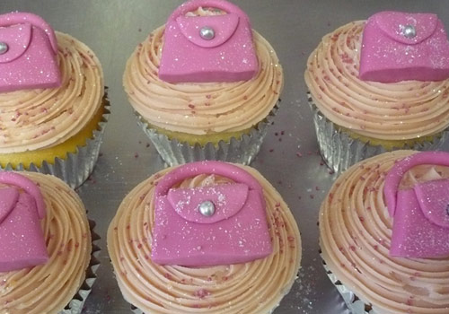 Cup cakes with pink iced handbags on them